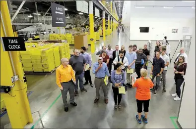  ?? AP/JULIO CORTEZ ?? An Amazon employee (bottom right) gives visitors a tour of an Amazon warehouse in Robbinsvil­le Township, N.J., on Aug. 2, the day Amazon hosted a nationwide job fair.