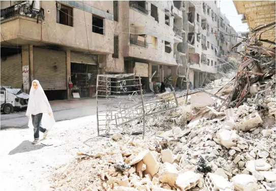  ??  ?? A girl walks past the rubble of a destroyed building down a street in the rebel-held Syrian town of Ayn Tarma, in the Ghouta area east of the capital Damascus on Wednesday. (AFP)