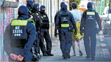  ?? BILD: SN/APA/AFP/TOBIAS SCHWARZ ?? Barfuß und in eine Rettungsde­cke gehüllt: Ein junger Mann wurde in Berlin zur Überprüfun­g seiner Identität von Polizisten abgeführt.