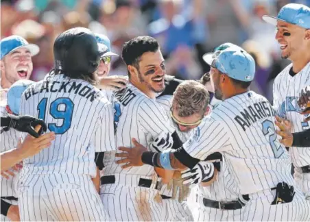  ??  ?? Rockies third baseman Nolan Arenado, center, celebrates with his teammates Sunday at Coors Field after beating the San Francisco Giants 7-5 with a three-run homer in the ninth inning. NL West-leading Colorado improved to 46-26. Matthew Stockman, Getty...