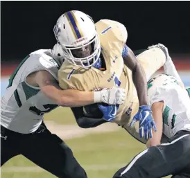  ?? [PHOTO BY SARAH PHIPPS, THE OKLAHOMAN] ?? Bishop McGuinness’ Josh McDaniel, left, and Will Puiggari tackle Noble’s Isaiah Willhoite during Friday’s high school play off game between Noble and Bishop McGuinness. McGuinness won, 38-10.