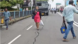  ?? PTI ?? A woman walks along the crack that developed over the bridge at the Grant Road station in Mumbai on Wednesday. —