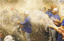  ?? Lachlan Cunningham / Getty Images ?? The Dodgers celebrate in the visiting locker room after beating the Giants at AT&amp;T Park to clinch a spot in the playoffs.