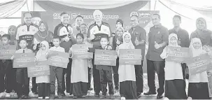  ?? — Gambar Bernama ?? MENERIMA SUMBANGAN: Najib (tengah) bergambar bersama murid-murid sekolah yang menerima sumbangan pembukaan akaun Skim Simpanan Pendidikan Nasional (SSPN-i) ketika Program UMNO Bantu Rakyat di Kampung Tanjung Medang, Pekan, semalam.