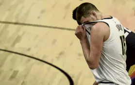  ?? AAron Ontiveroz, The Denver Post ?? Denver’s Nikola Jokic (15) wipes sweat from his face as Devin Booker shoots free throws during the third quarter of Monday night’s game in Phoenix.