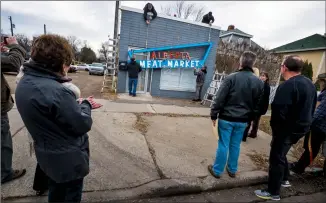  ?? Herald photo by Ian Martens ?? A crew lowers the Alberta Meat Market sign from its fittings Thursday as a small crowd of Galt Museum staff and others with connection­s to the past and future aspects of the historic building look on. @IMartensHe­rald