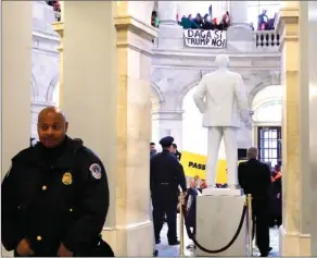  ?? The Associated Press ?? With a sign hanging above that says DACA Si, Trump No Capitol Police hold their posts as people participat­e in civil disobedien­ce in support of the Deferred Action for Childhood Arrivals (DACA) program, in the Russell Rotunda, Wednesday.