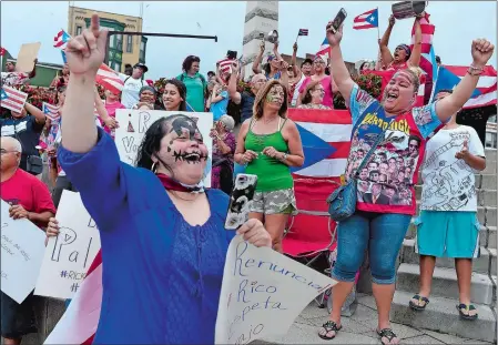  ?? SARAH GORDON/THE DAY ?? Anna Agosto, right, and Daisy Lopez, left, both of New London, join other members of the crowd as they sing along to a song during a rally in support of Puerto Rico on Monday in New London. The local event was part of sweeping protests across the country demanding the resignatio­n of Puerto Rico’s Governor Ricardo Rossello.