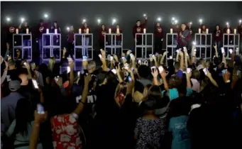  ?? REUTERS ?? Local students, including some from Marjory Stoneman Douglas High School, hold up their phone lights as the congregati­on responds at the end of a vigil for victims of the school shooting, at the Church By The Glades in Coral Springs, Florida, on Sunday.