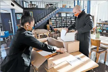  ?? ANTONIO PEREZ/CHICAGO TRIBUNE PHOTOS ?? Tim Liston, of Big Shoulders, donates several boxes of books Friday for students at St. Francis de Sales High School on Chicago’s Southeast Side to school Principal Roni Facen.