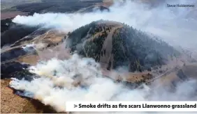  ?? Steve Holderness ?? > Smoke drifts as fire scars Llanwonno grassland