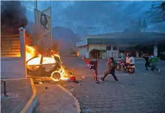  ??  ?? Un hombre lanza una bandera del partido del actual gobierno nicaragüen­se hacia un vehículo en llamas, durante las protestas de ayer en Managua.