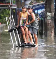  ??  ?? Boys rest on a partially submerged bumper of a vehicle along a flooded street caused by monsoon rains and tropical storm Henry in Quezon city, Metro Manila, yesterday.