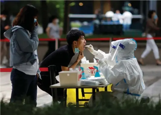  ?? ?? ► Un trabajador médico toma muestras de un residente, durante una prueba masiva de Covid en el distrito de Chaoyang, en Beijing.