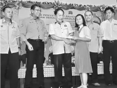  ??  ?? Wong (third left) presents a school uniform voucher to a student while (from left) Stanley, Azmi, Awang Yusup and Chong Kung look on.