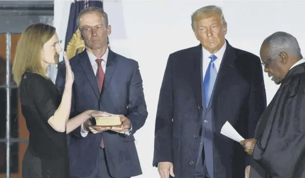  ??  ?? 0 Donald Trump watches as Supreme Court Justice Clarence Thomas swears in Amy Coney Barrett as a Supreme Court Justice, watched by her husband Jesse Barrett