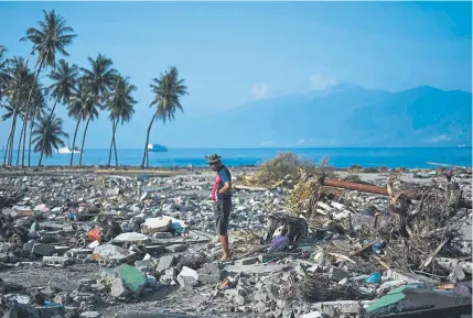  ?? Jewel Samad, Getty Images ?? A survivor stands among the debris of his obliterate­d neighborho­od in Indonesia’s central Sulawesi on Wednesday. An earthquake and tsunami hit the area Sept. 28. More than 1,400 people have died in the disaster, and U.N. officials say the “needs remain vast” for desperate survivors and rescue teams still searching for victims.