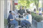  ?? GERRY BROOME — THE ASSOCIATED PRESS ?? Patrons are assisted while dining along a sidewalk on Franklin Street in Chapel Hill, N.C., on April 16.