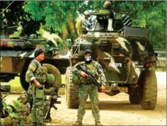  ?? MARK NAVALES/AFP ?? Philippine soldiers stand guard next to an armoured personnel carrier, on the southern island of Mindanao, as they prepare for an operation against the extremist Abu Sayyaf last year.