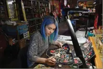  ??  ?? Artist Xochitl Burciaga paints a design on a pair of custom boots at Rocketbust­er in El Paso, Texas.