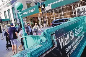  ?? RICHARD DREW/ASSOCIATED PRESS ?? People walk on Broadway at Wall Street in June 2021. The Dow Jones Industrial Average sank more than 1,100 points and the S&P 500 had its biggest drop in nearly two years Wednesday.