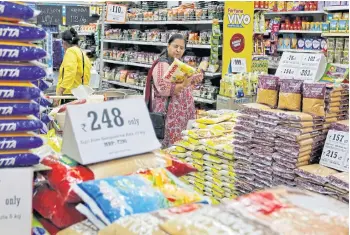  ??  ?? A customer looks at an item as she shops in a food superstore in Ahmedabad, India.