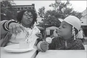  ?? Arkansas Democrat-Gazette/THOMAS METTHE ?? Lacy Higgins (right), 3, munches on a cornbread fritter while her mother, Latonya, goes through her cornbread samples for judging during the ninth annual Arkansas Cornbread Festival on Saturday in Little Rock.