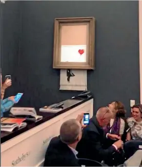  ?? AP ?? Art buyers watch as the spray-painted canvas Girl with Balloon by artist Banksy is shredded at Sotheby’s, in London.