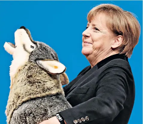  ??  ?? Friend in need: Angela Merkel holds a toy wolf she was given at the Christian Democrats’ party conference, in which she was forced to quell disquiet over her refugee policy