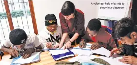  ??  ?? A volunteer help migrants to study in a classroom