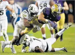  ?? Thearon W. Henderson Getty Images ?? WASHINGTON’S Myles Gaskin, who rushed for 159 yards as the Huskies’ passing game struggled, is brought down by Colorado’s Kenneth Olugbode.