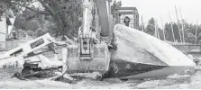  ??  ?? An excavator removes a boat from Cadboro Bay beach.