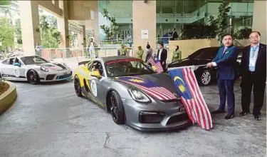  ?? PIC BY MOHD FADLI HAMZAH ?? Transport Minister Anthony Loke (second from right) flagging off a convoy of 22 Porsche sports cars heading for Bangkok for the 70th Porsche anniversar­y celebratio­n, in Putrajaya yesterday.