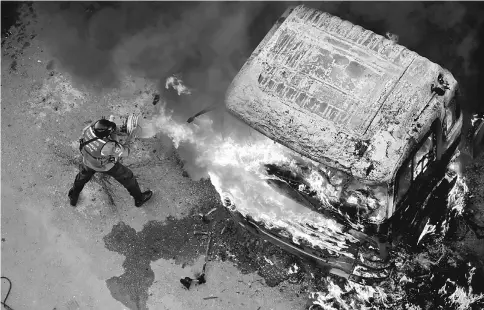  ??  ?? A fireman tries to extinguish a fire during a rally against Maduro in Caracas, Venezuela in this file photo. — Reuters photo