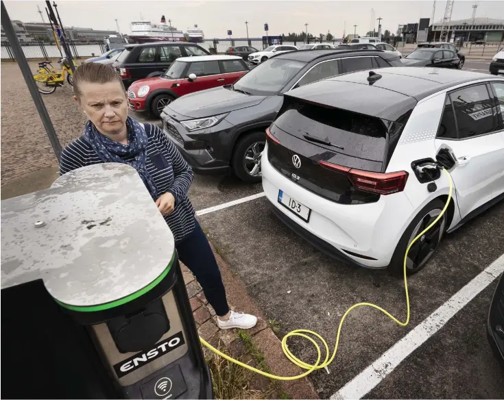  ?? FOTO: TIMO KARI ?? Hanna Ojamo laddar sin Volkswagen ID.3 vid Gamla saluhallen i Helsingfor­s. Modellen kom ut på marknaden i fjol och hör till de populärast­e elbilsmode­llerna i Finland.