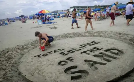  ?? PETE MAROVICH/GETTY IMAGES ?? Val Carney, of Asheville, N.C., builds her sand tribute to the solar eclipse as observers wait for the clouds to clear