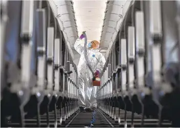  ?? AARON ONTIVEROZ GETTY IMAGES ?? Brandon Wilson, owner of Avidjet, uses a fogger filled with a microbiost­atic agent to disinfect a Frontier airliner at Denver Internatio­nal Airport.