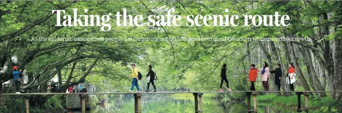  ?? SHI GUANGDE / FOR CHINA DAILY ?? Visitors walk on a bridge at a wetland park in Huangshan, Anhui province, on April 10.