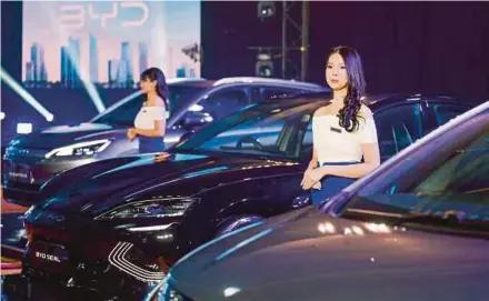 ?? AFP PIC ?? Models standing in between three types of China-made electric vehicles at the launch of the BYD brand in Jakarta last month.
