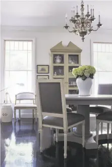  ?? Erica Johnston ?? An ivory palette unifies the open-plan living and dining areas. The dining area, above, features a $200 table from a warehouse sale. In the living room, right, the sofa has been Scotchgard­ed, and the framed maps behind it are from a book that cost $1.