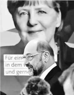  ??  ?? Schulz walk past a poster Merkel on his arrival for talks at the Konrad Adenauer building, the Christian Democratic Union (CDU) headquarte­rs in Berlin. — AFP photo
