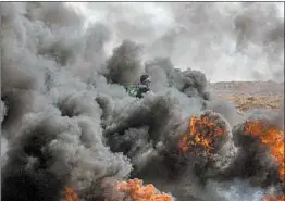  ?? MOHAMMED SABER/EPA ?? A protester stands amid smoke billowing from a barricade of burning tires Friday during clashes between Palestinia­ns and Israeli troops near the border of eastern Gaza Strip.