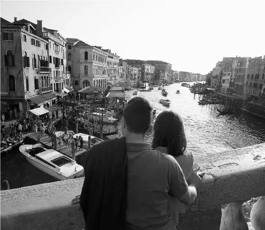  ?? Luca Bruno / The Associat ed Press ?? Tourists enjoy the view from the Rialto bridge in Venice Thursday. Venice city officials are closing a walkway fronting the picturesqu­e Grand Canal on Monday to keep crowds away from actor George Clooney’s wedding.