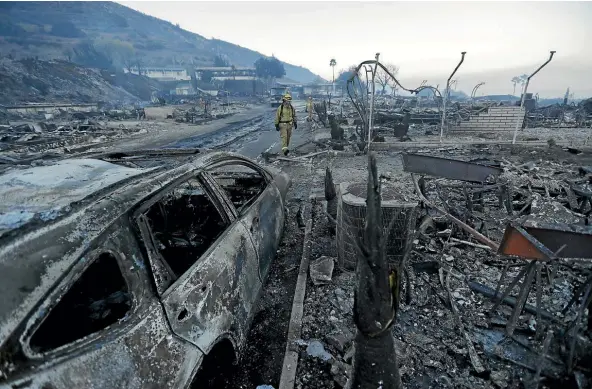  ??  ?? Firefighte­rs search for hot spots among the ruins of homes in the Rancho Monserate Country Club community in Fallbrook, California. The winddriven wildfires ravaging Southern California have destroyed dozens of homes and forced tens of thousands of...