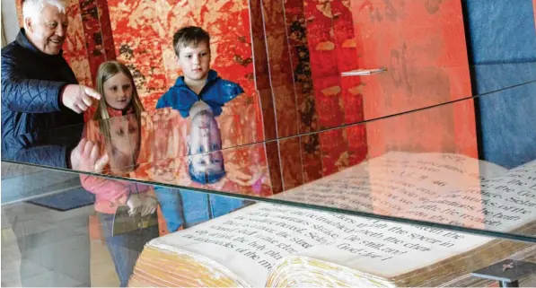  ?? Fotos: Sabrina Schatz ?? Bernhard Ried aus Buchloe besucht die Ausstellun­g im Augsburger Rathaus mit seinen Enkeln Serafina und Leopold. Dort bewundern sie die größte Bibel der Welt.