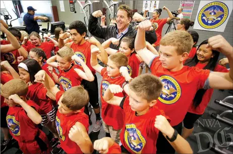  ?? NWA DEMOCRAT-GAZETTE/ DAVID GOTTSCHALK ?? Jake Steinfeld (back center), chairman of the National Foundation for Governors’ Fitness Councils and personal fitness television personalit­y, poses with Lincoln Middle School students as they display their muscles within the new Live Positively...