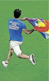  ?? | Reuters ?? A PITCH invader runs onto the pitch wearing a t-shirt with a message saying ‘Respect for Iranian Women’ and holding a rainbow flag during the match.