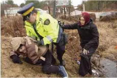  ??  ?? An RCMP officer helps asylum seekers, claiming to be from Turkey, cross the border from New York into Canada in Hemmingfor­d, Quebec. America’s neighbor to the north has been increasing­ly seen as a heaven for some immigrants who are willing to chance a walk across the border in sometimes dangerous cold to get there. — AP