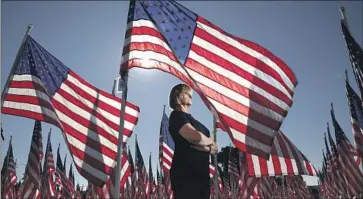  ?? Irfan Khan Los Angeles Times ?? LINDA LOGAN, who started the Covina Rotary Club’s Field of Valor 11 years ago to help veterans, stands amid the installati­on of f luttering f lags on the grounds of Sierra Vista Middle School on Saturday in Covina.