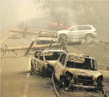  ?? JUSTIN SULLIVAN / GETTY IMAGES ?? Power lines rest on burned cars Saturday in Paradise, Calif. The massive Camp Fire blaze is now the most destructiv­e wildfire in California history. More than 100 area residents remained missing on Sunday.